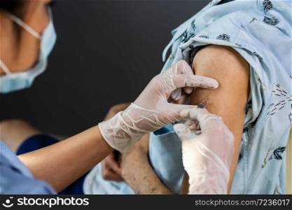 close up doctor in gloves holding syringe and making injection to patient in medical mask. Covid-19 or coronavirus vaccine