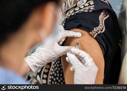 close up doctor in gloves holding syringe and making injection to patient in medical mask. Covid-19 or coronavirus vaccine