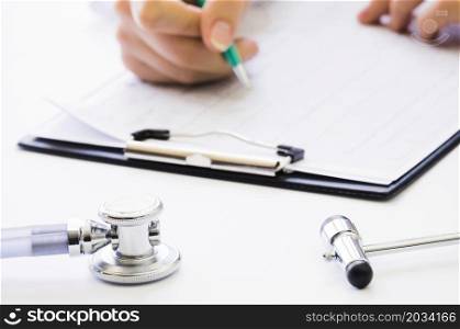 close up doctor s hand holding pen checking medical report clipboard