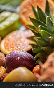 Close-up droplets of water on passion fruits, evergreen tropical pineapple leaves with shalow depth of field. Exotic tropical vegetarian concept background.. Tropical fresh background with exotic Passion fruit in a droplets of water and green pineapple leaves. Sallow depth of field.