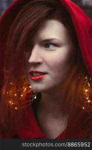 Close up elegant woman with fairy lights and hood portrait picture. Closeup side view photography with blurry background. High quality photo for ads, travel blog, magazine, article. Close up elegant woman with fairy lights and hood portrait picture