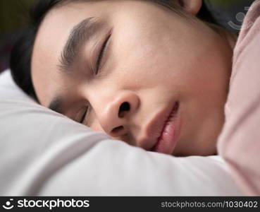 Close up face of Asian young woman sleeping well in bed hugging soft white pillow. Health care concept.