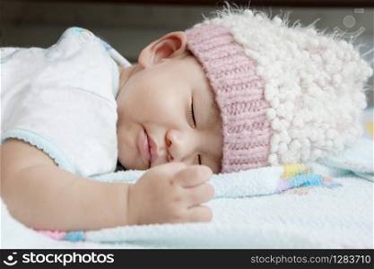 close up face of baby sleeping on clothes bed wearing wool hood