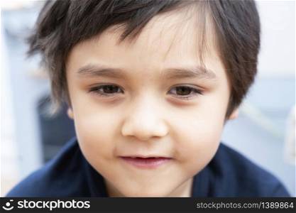Close up face of handsome boy with little smile, Candid short of healhty happy chile boy face with sunny day light, Positive children concept