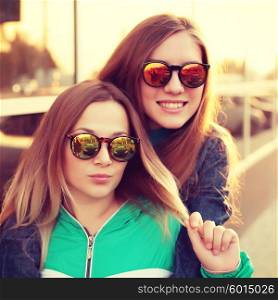 Close up fashion portrait of two young hipster girl friends, wearing mirrored sunglasses, having blonde and ombre hairs