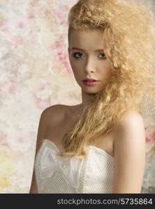 close-up fashion shoot of cute blonde woman with stylish hair-style, natural make-up and elegant white dress looking in camera