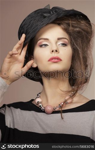 close-up fashion shoot of pretty female with lovely black hat, striped dress and necklace
