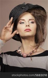 close-up fashion shoot of pretty female with lovely black hat, striped dress and necklace