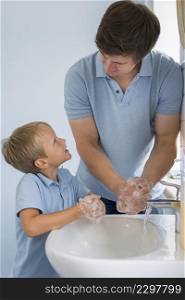 close up father teaching son how wash hands