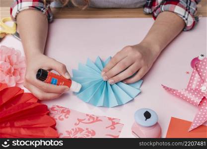 close up female artist sticking blue origami paper fan