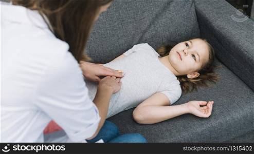 close up female doctor examining patient girl lying gray sofa