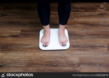 Close-up female feet stepping on body weight scale. Weight control, weight loss concept.