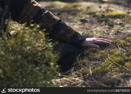 Close up female hand in ethnic clothes touching grass concept photo. Connect with nature. Side view photography with blur background. High quality picture for wallpaper, travel blog, magazine, article. Close up female hand in ethnic clothes touching grass concept photo