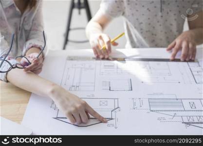 close up female hand pointing blueprint table workplace