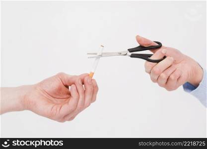 close up female s hand cutting cigarette with scissor from man s hand