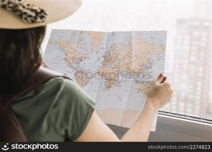 close up female tourist reading map near window