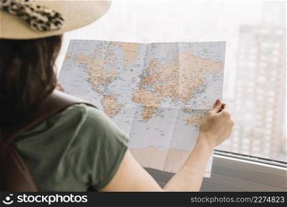close up female tourist reading map near window