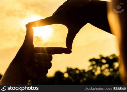 Close up finger frame of asian woman at sunset background. Silhouette picture