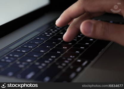 close-up finger typing on keyboard computer working at night