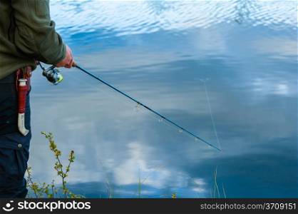 Close-up, fisherman casts a lure on the lake, horizon format image