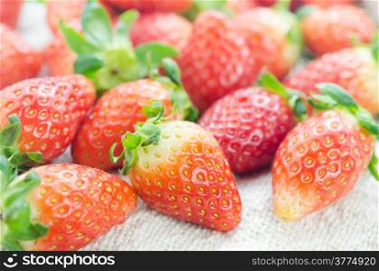 close up fresh red strawberries over sackcloth , ripe fruit