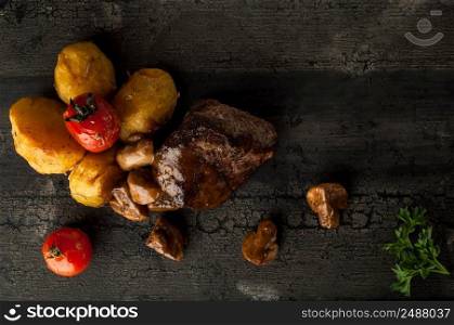 close-up fried meat with potatoes on a wooden old board. fried meat with potatoes and mushrooms on a wooden old surface. dish on a wooden surface