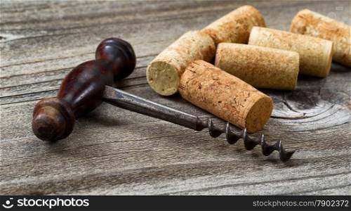 Close up front view of antique corkscrew with used corks in background on rustic wood. Horizontal layout. &#xA;&#xA;