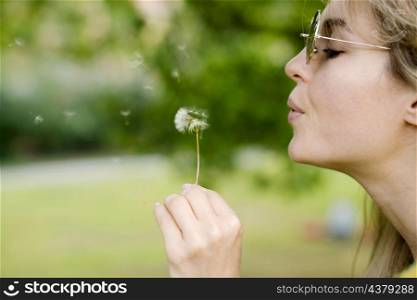 close up girl blowing dandelion