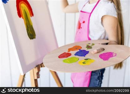 close up girl painting canvas holding multicolored wooden palette hand