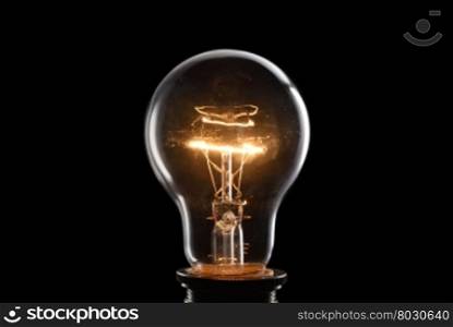 Close up glowing vintage light bulb. Isolated on black background
