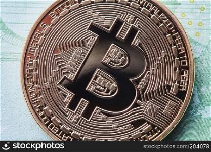 Close up golden bitcoin metallic coin over paper money euro banknotes. Bitcoin cryptocurrency. Business concept and future financial technology concept. Close up golden bitcoin on Euro background. Bitcoin cryptocurrency.