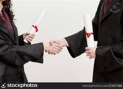 close up graduates shaking hands