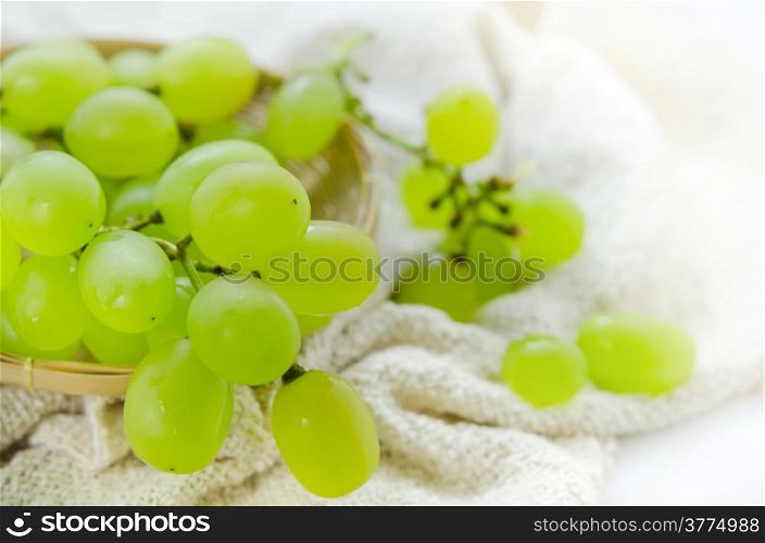 close up green grape in wooden basket over sackcloth. green grapes