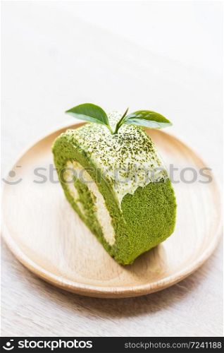 Close up green tea roll cake on wooden dish,shallow Depth of Field,Focus on tea leaves.. Close up green tea roll cake.