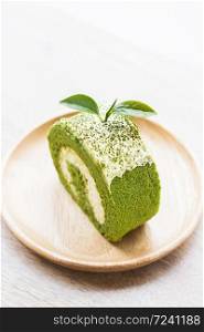 Close up green tea roll cake on wooden dish,shallow Depth of Field,Focus on tea leaves.. Close up green tea roll cake.