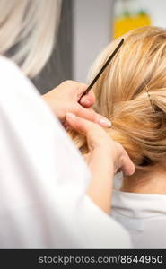 Close-up hairdresser styling blonde hair on the back of the head in a beauty salon. Close-up hairdresser styling blonde hair on the back of the head in a beauty salon.