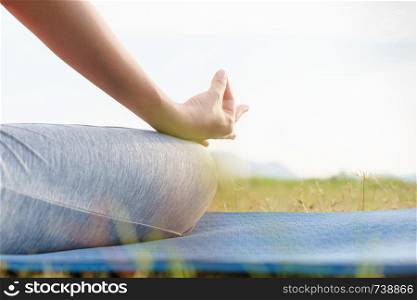 close up hand and half body of health woman sit in lotus yoga position in the morning at park. Practicing yoga makes meditation for healthy breathing and relaxation