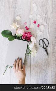 close up hand holding book with hydrangea roses flowers scissor wooden plank