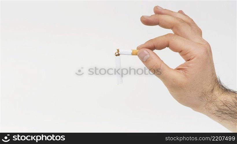 close up hand holding broken cigarette against white backdrop
