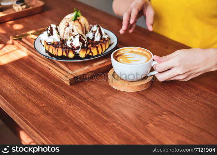 Close up Hand holding coffee cup of People are in coffee shop