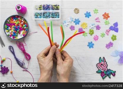 close up hand holding colorful chenille stems with decorative elements