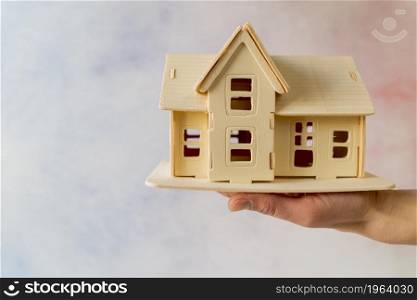 close up hand holding house model against textured background. High resolution photo. close up hand holding house model against textured background. High quality photo