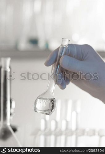 close up hand holding lab glassware
