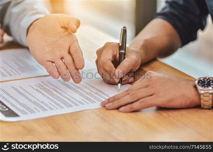Close up hand holding pen sign contract on document
