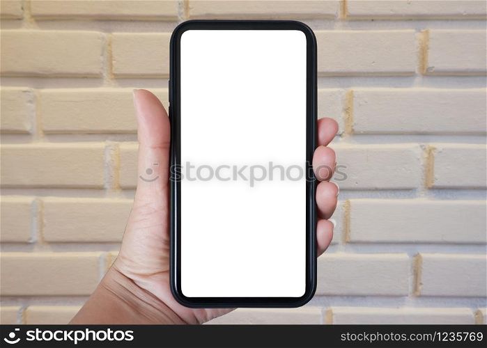 Close-up hand holding phone vertical, Using smart phone towards white brick wall background - copy space.
