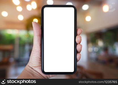 Close-up hand holding phone vertical, Using smart phone with blurred background of house, cafe interior - copy space.