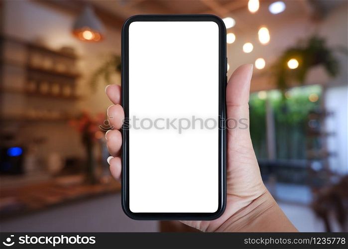 Close-up hand holding phone vertical, Using smart phone with blurred background of house, cafe interior - copy space.