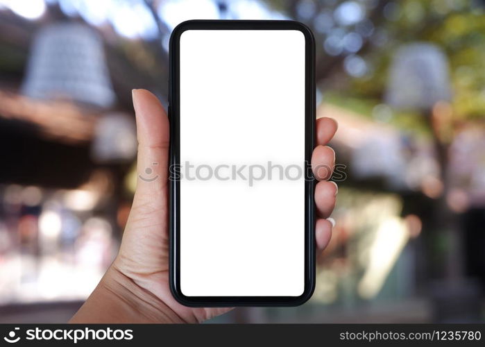 Close-up hand holding phone vertical, Using smart phone with blurred background of house, cafe interior - copy space.