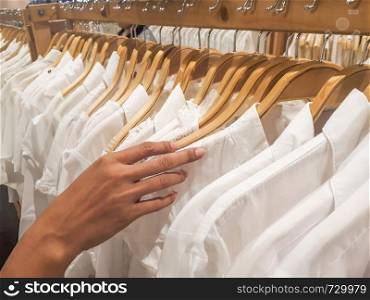 Close up hand holding white shirts fashion for women in shopping mall