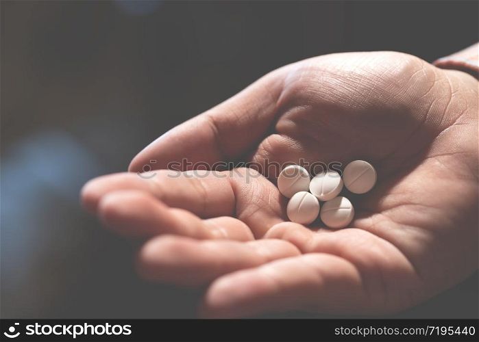 close up hand man holding taking multiple pills. Stop drug use Taking Medication health care medical concept. narcotic sleeping pills dark background.